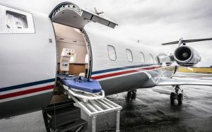 Пустые носилки на погрузочной платформе у открытой двери санитарного самолёта