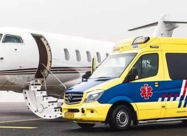 Gelb-blauer Krankenwagen neben einem geöffneten Ambulanzflugzeug