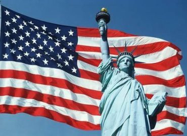 Freiheitsstatue vor einer US-amerikanischen Flagge